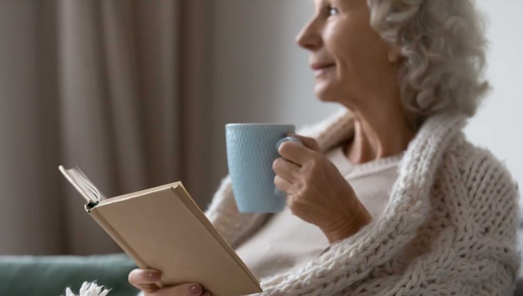 Women reading book with coffee in hand