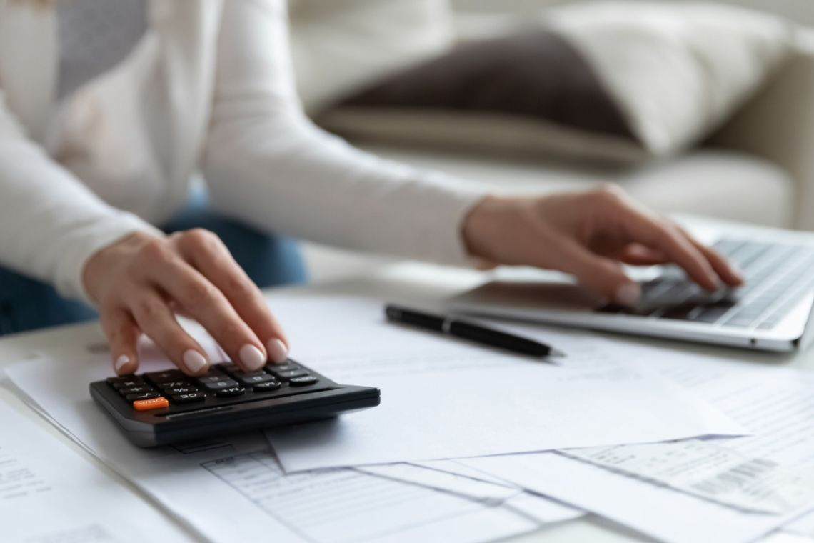 woman undertaking calculations with laptop and calculator