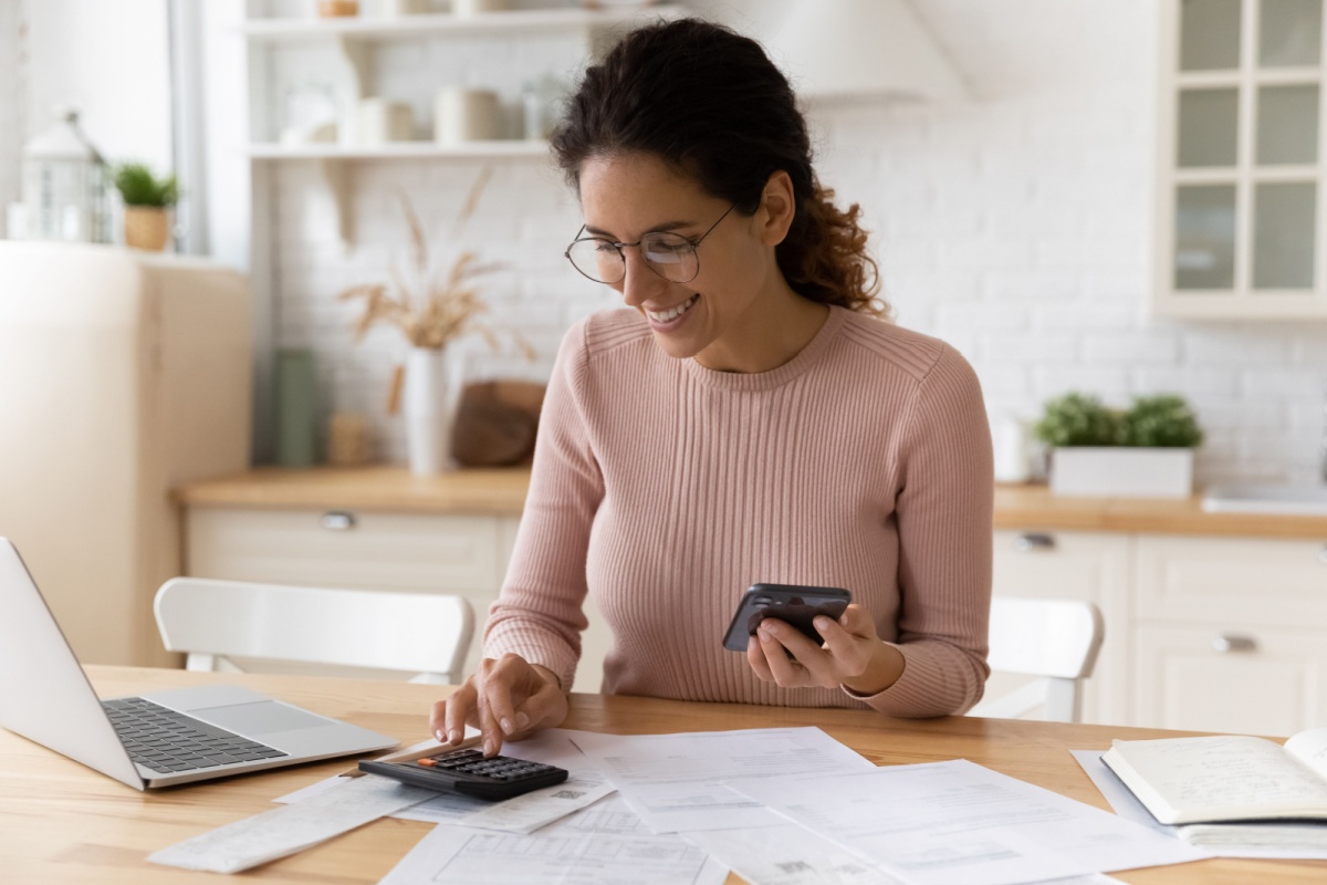 Happy woman using a calculator and laptop