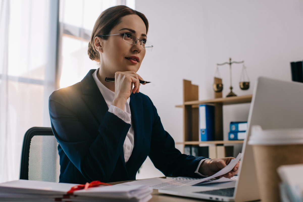 Female solicitor working on a laptop and reviewing paperwork