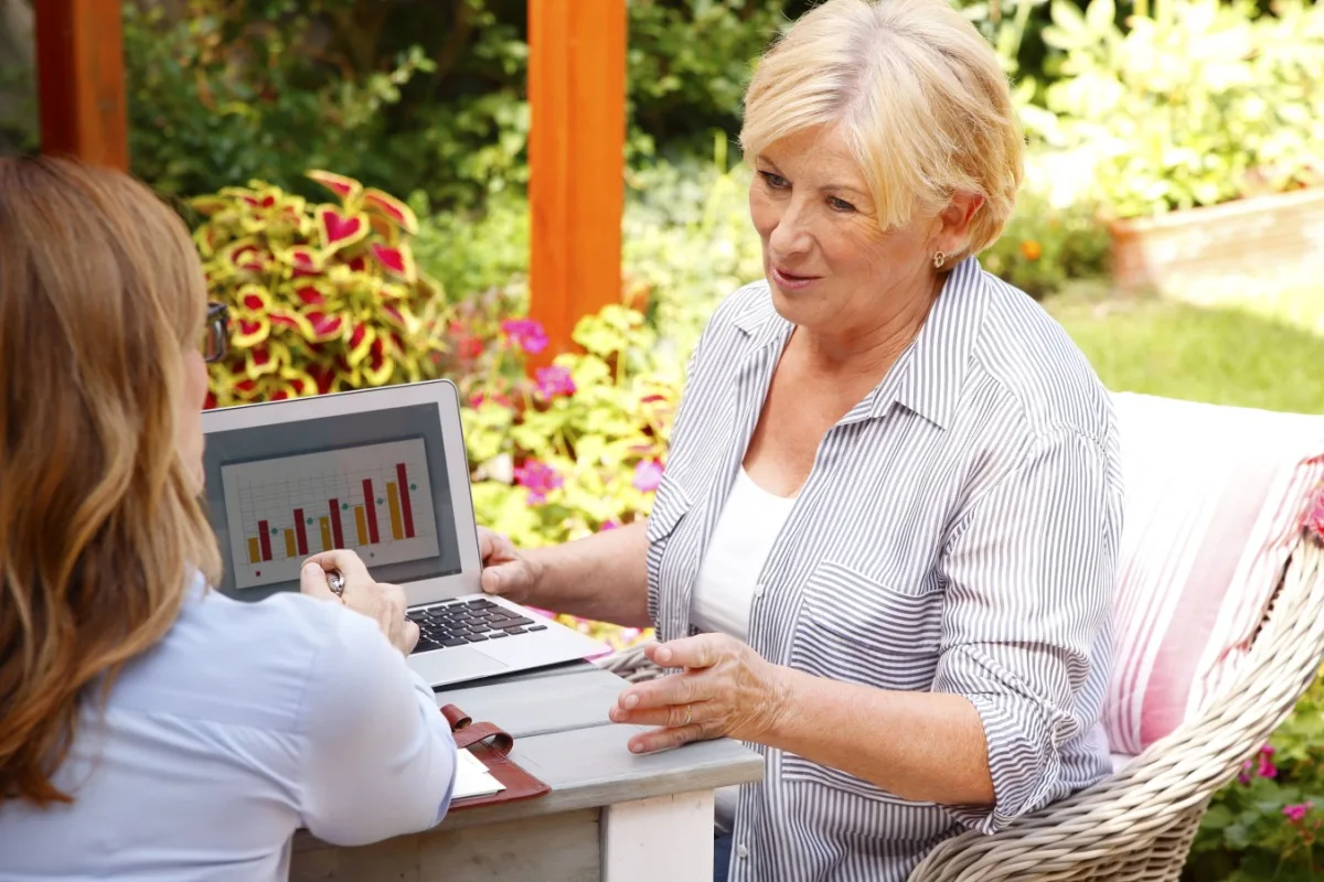 Financial expert showing a senior woman charts on a laptop