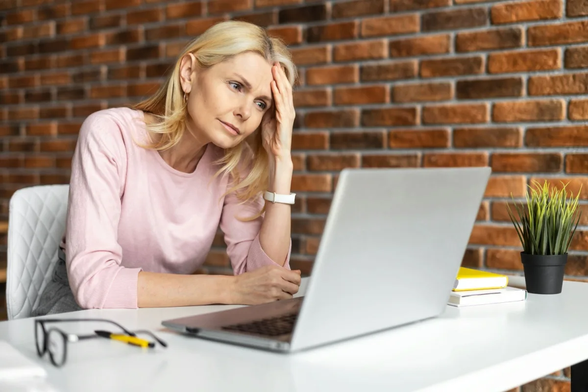Confused middle-aged woman looking at a laptop