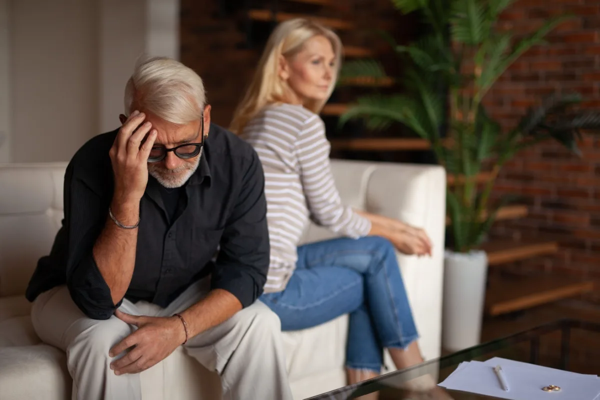 Sad middle-aged couple sitting on a sofa with their backs to each other