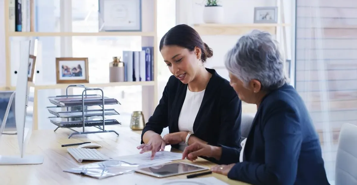 Financial planner looking at paperwork and a tablet with a female client