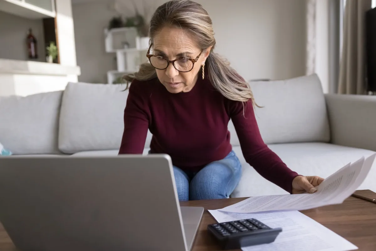 Mature woman looking at her laptop and financial paperwork