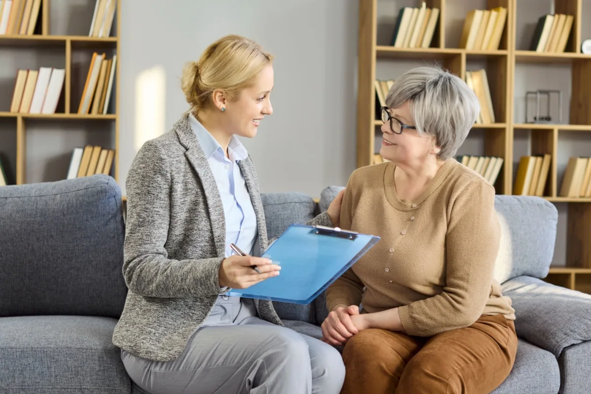 Friendly female financial expert and a senior woman sitting on a sofa talking