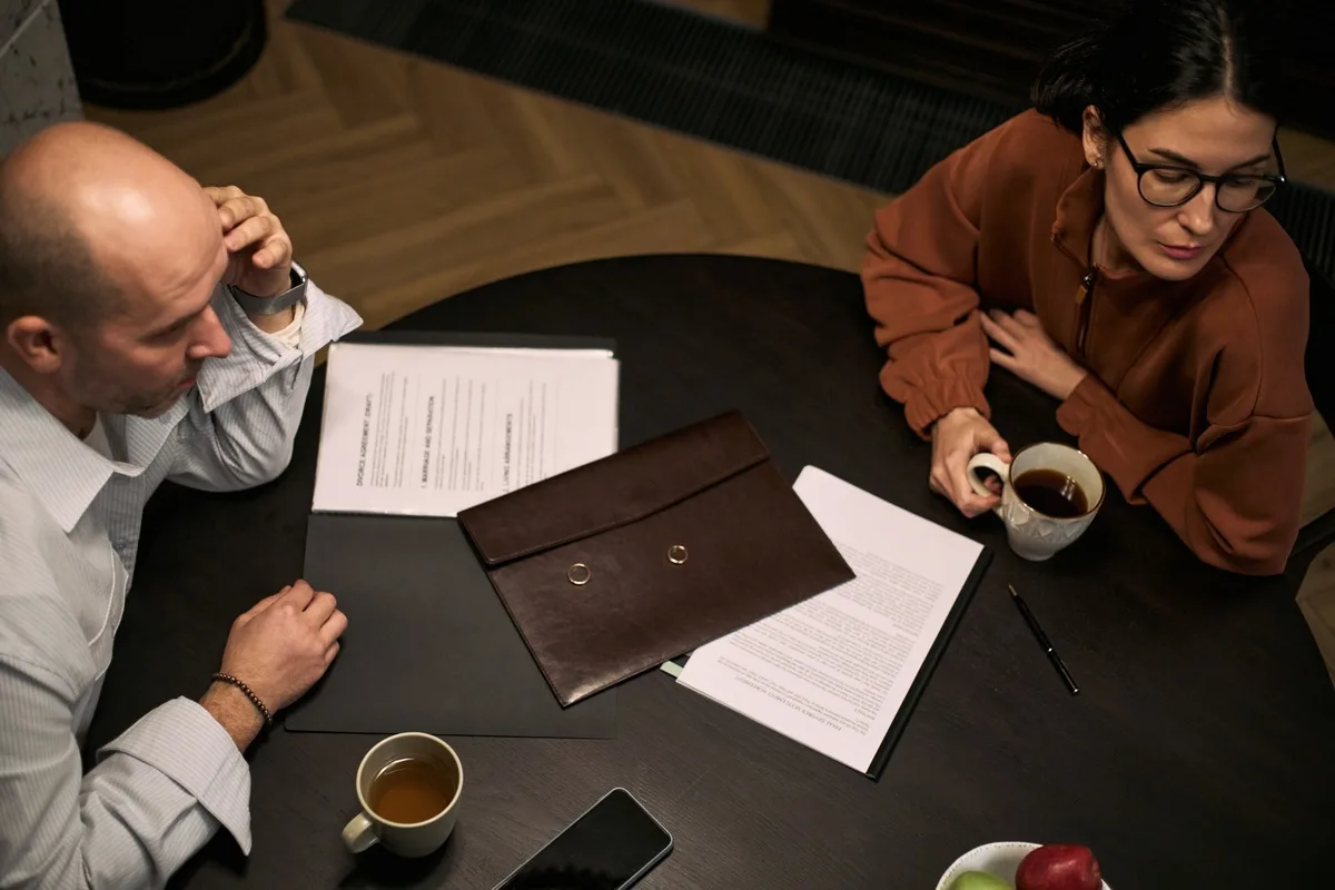 Middle-aged couple with divorce papers sitting apart in conflict